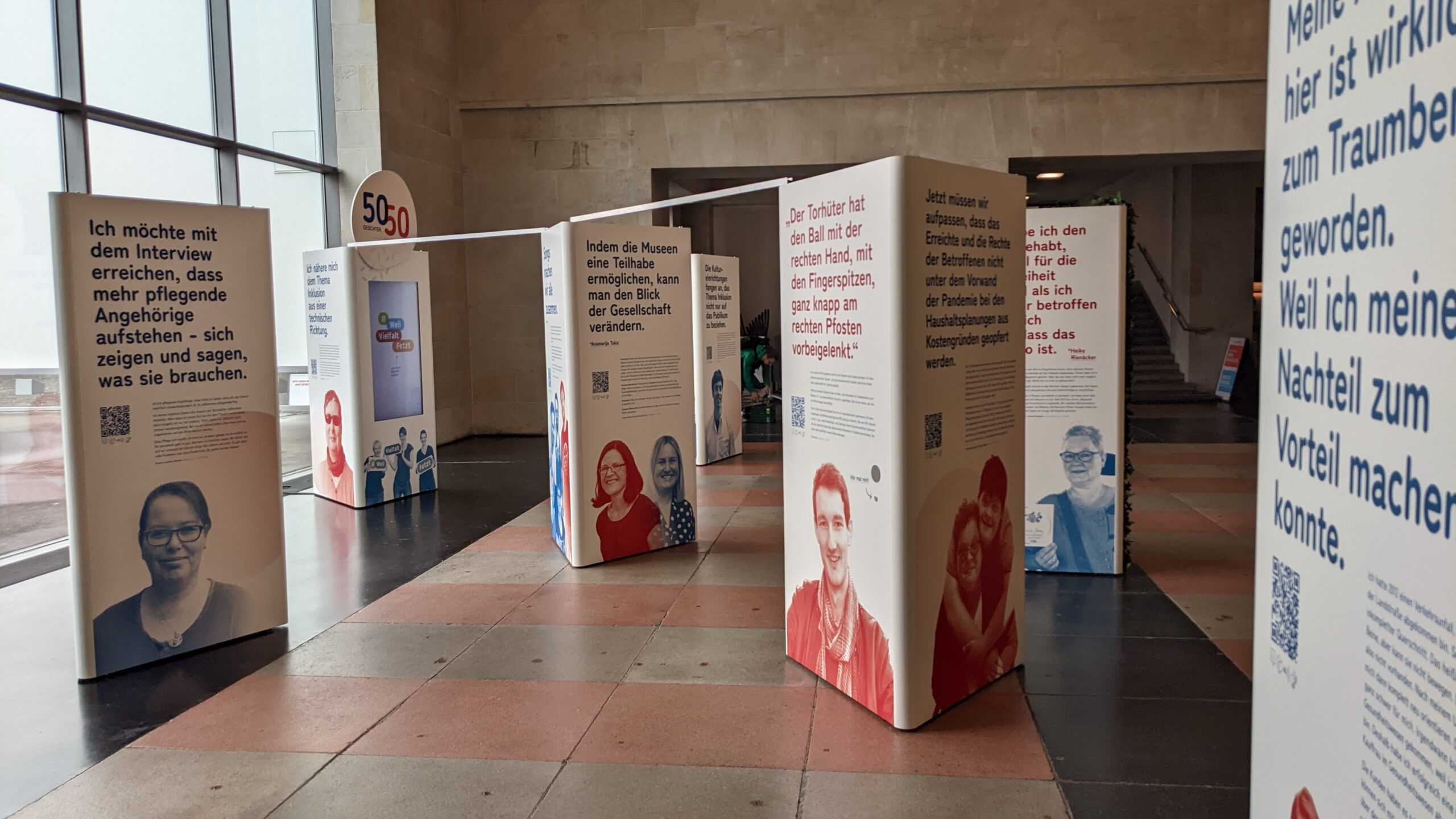 Die Porträtwände der Ausstellung auf dem Steinfußboden des Foyers